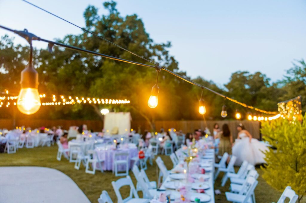 A beautiful outdoor wedding reception setup in Las Vegas with string lights and tables decorated affordably. — budget we…
