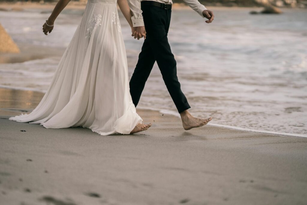 A bride and groom walking barefoot on the sand during their wedding. — stress-free beach wedding Las Vegas