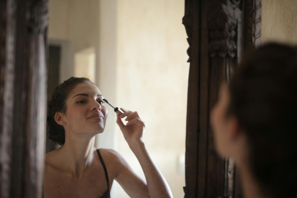 A bride applying waterproof mascara on the beach. — beach wedding makeup Las Vegas
