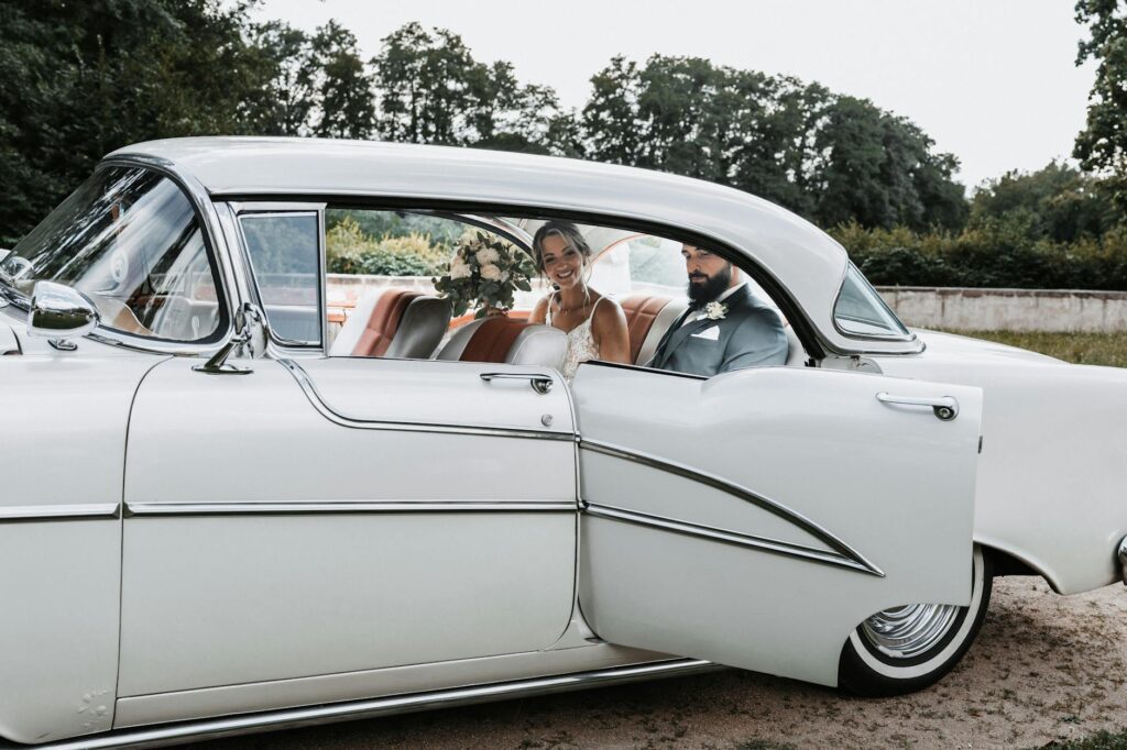 A cheerful couple stepping out of a classic car, showcasing affordable wedding transport options. — affordable wedding t…