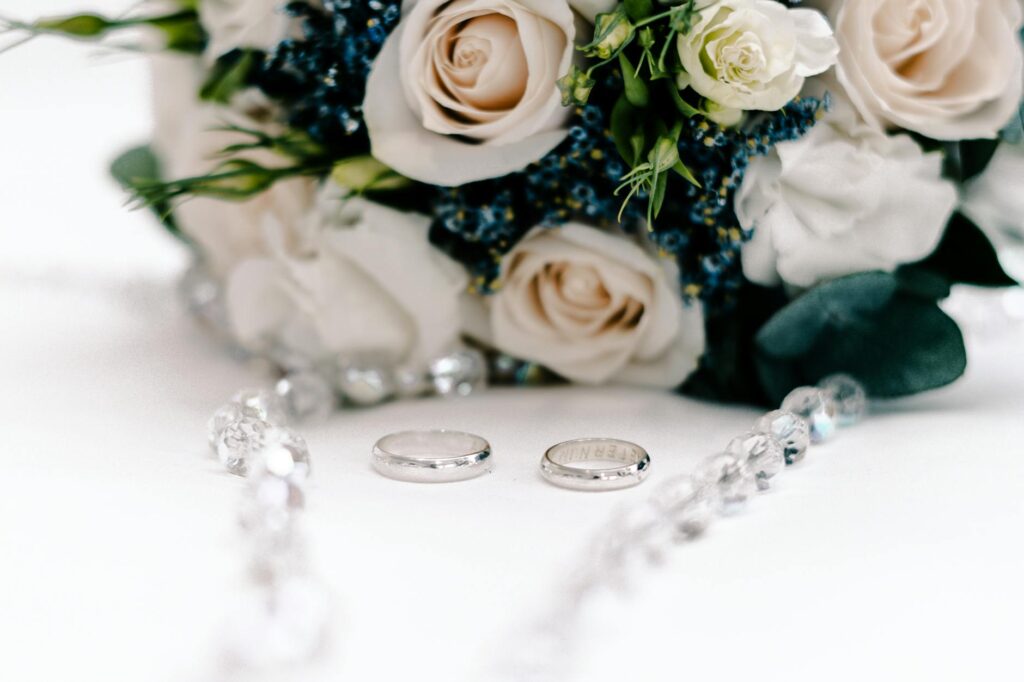 A close-up of wedding details like rings, flowers, and a beach-themed invitation. — beach wedding packages Las Vegas