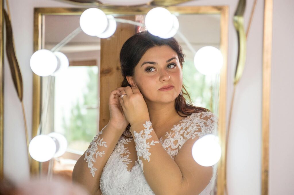 A happy bride admiring her reflection after receiving professional wedding beauty services. — affordable wedding hair ma…
