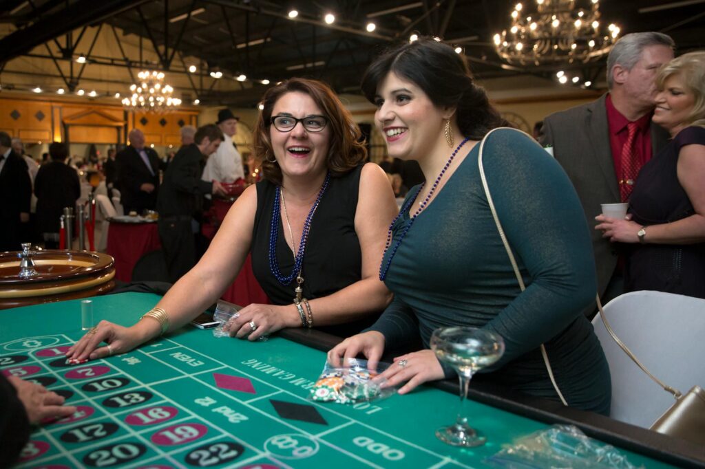A lively casino-themed wedding after-party with guests playing blackjack — casino wedding after-party ideas