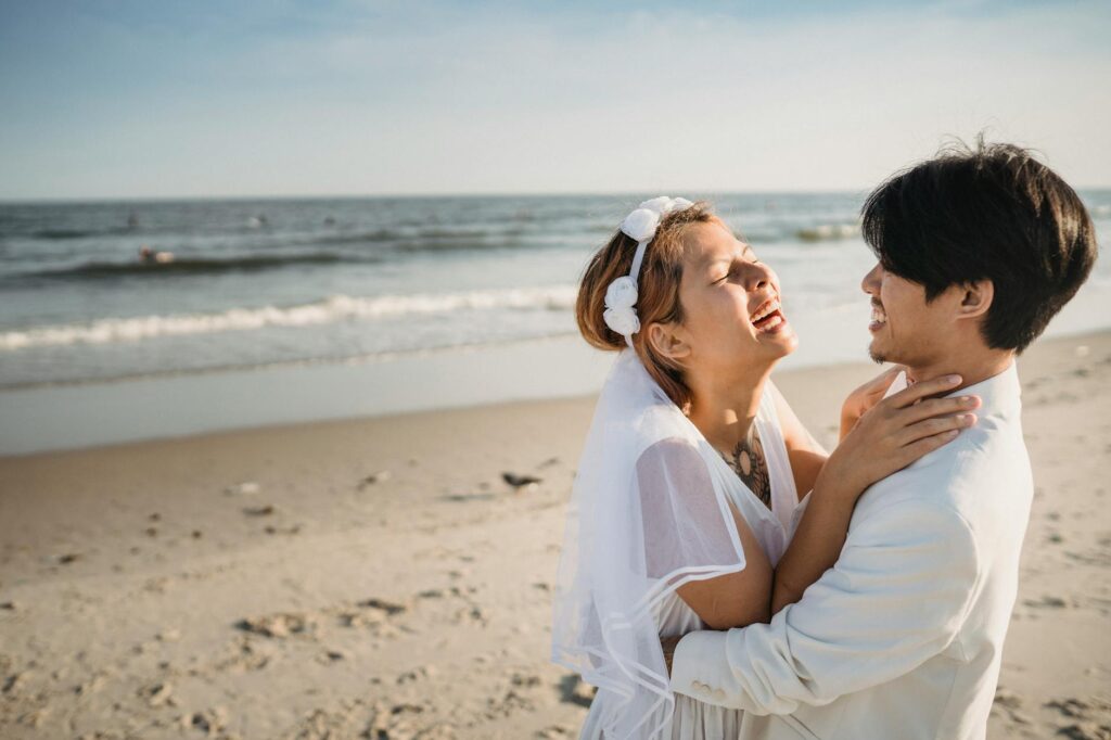 A stylish bride and groom wearing eco-friendly attire on the beach, showcasing their commitment to sustainability. — eco…
