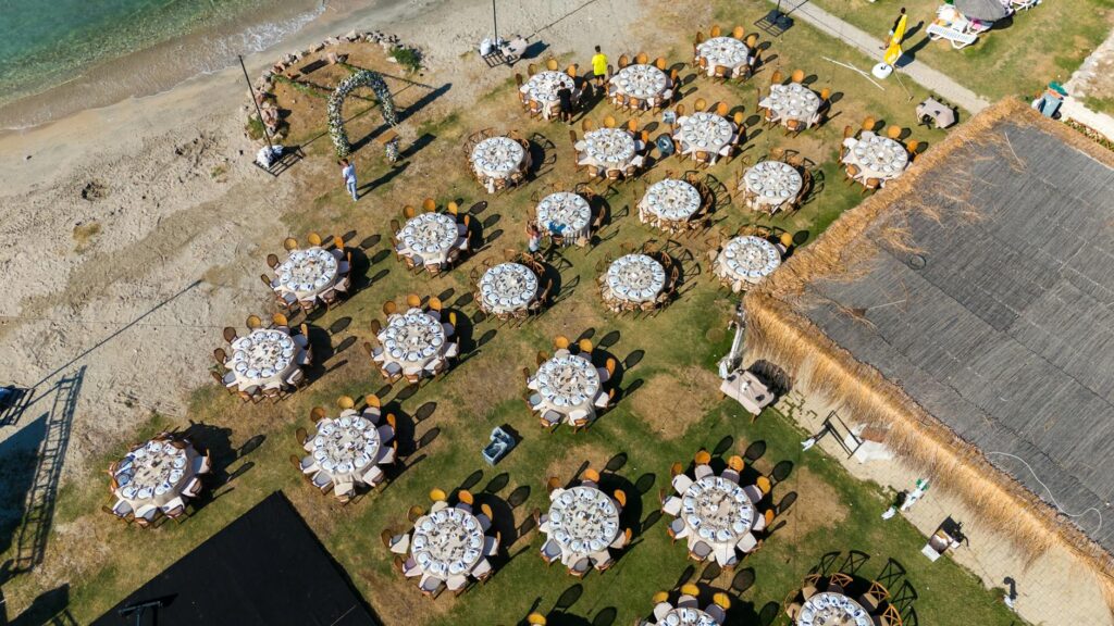 An outdoor reception setup with tables, lights, and music equipment by the beach. — beach wedding playlist Las Vegas