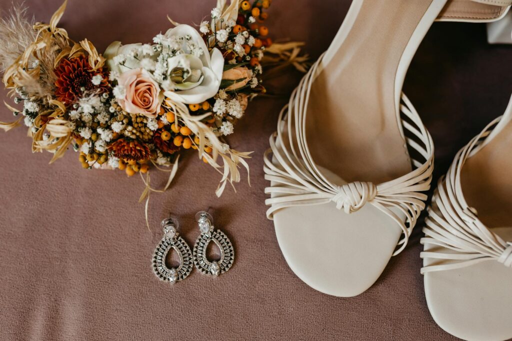 Close-up of bridal accessories like sandals and shell jewelry on a beach. — beach wedding dress Las Vegas