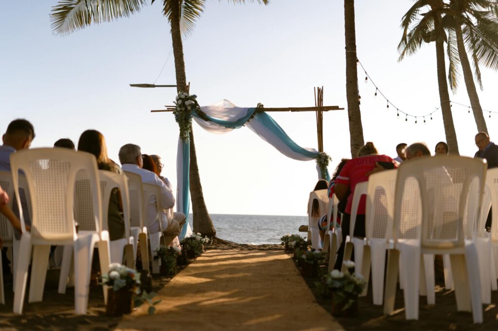 Guests enjoying a beach ceremony with palm trees in the background. — stress-free beach wedding Las Vegas