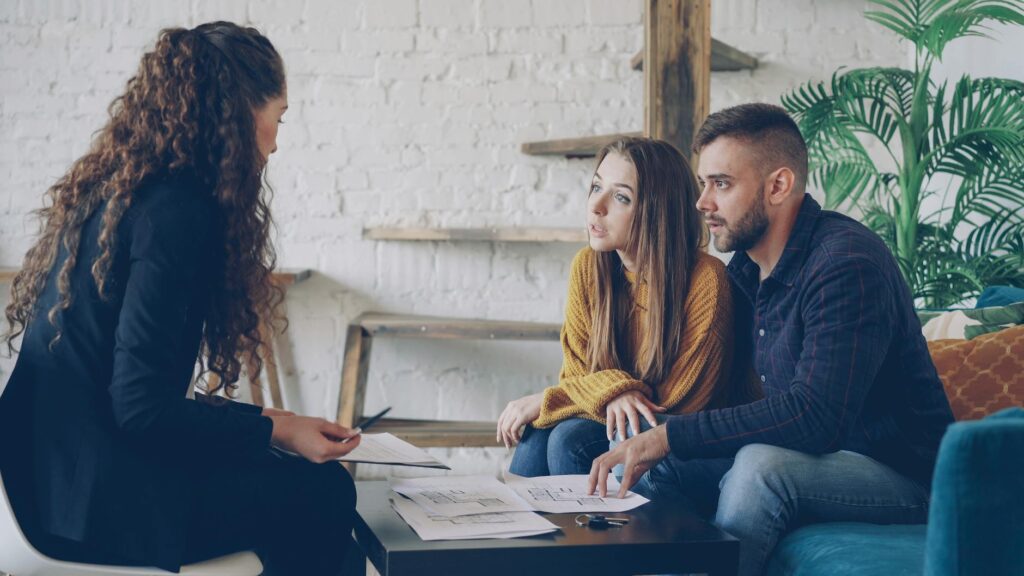 An engaged couple discussing plans with a Las Vegas wedding planner in a bright, airy office. — questions for wedding pl…
