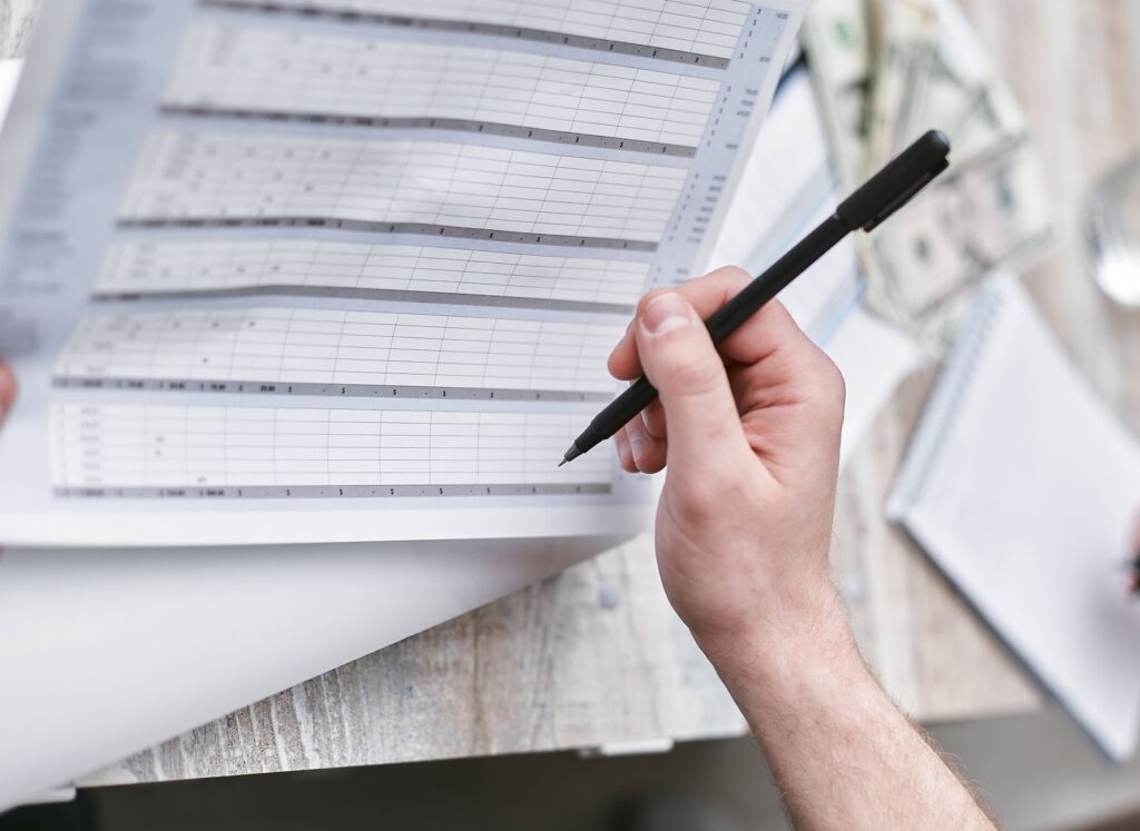 A close-up of wedding planner's hands working on a budget spreadsheet. — questions for wedding planner