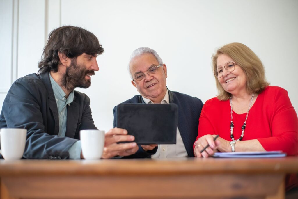 A smiling couple with their wedding concierge discussing plans on a tablet. — Las Vegas wedding concierge services